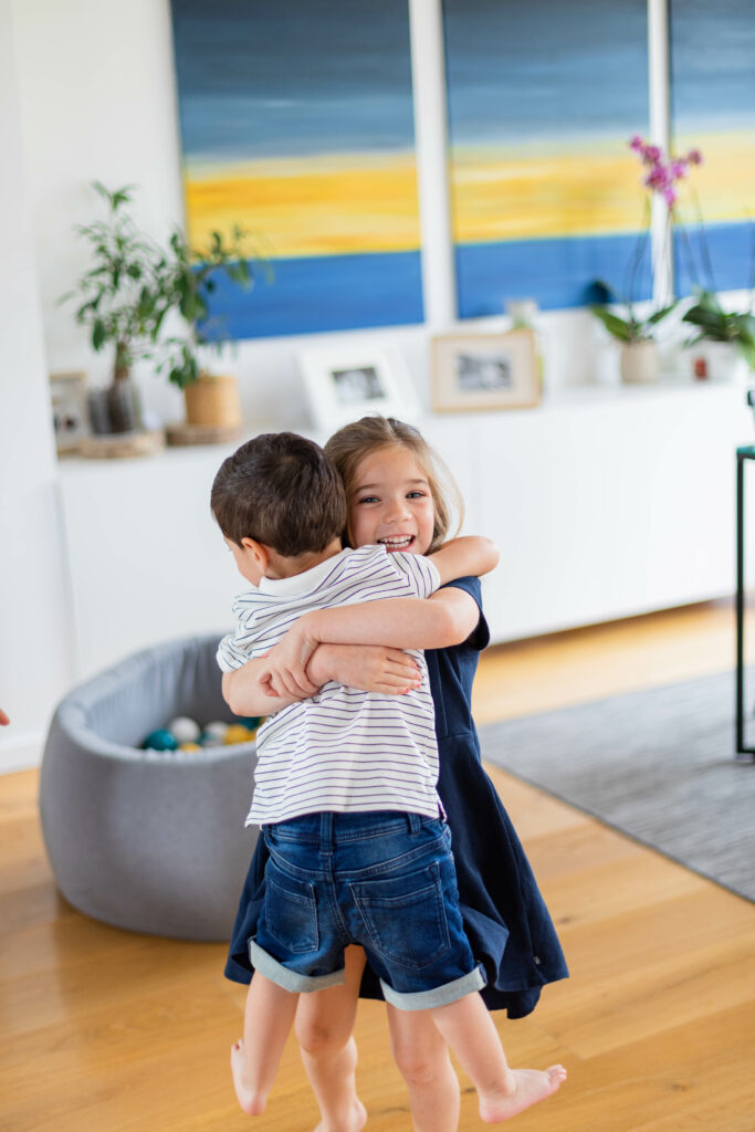 Frère et sœur qui se font un câlin dans le salon