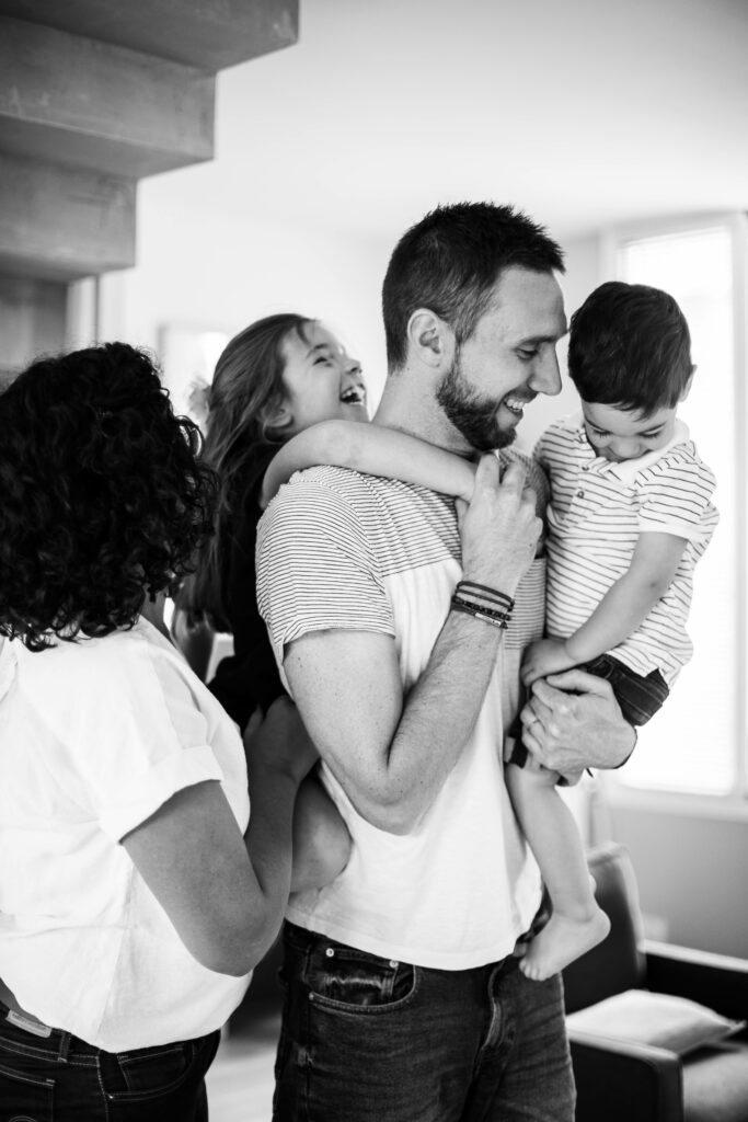 Papa qui porte ses enfants dans les bras, en noir et blanc