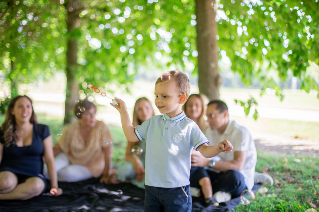 Famille qui pique-nique dans l'herbe à l'ombre des arbres