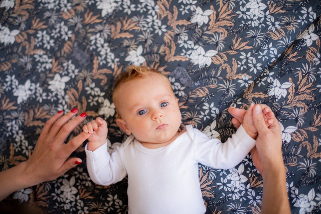 Bébé allongé sur un tissu fleuri, regard vers l'objectif