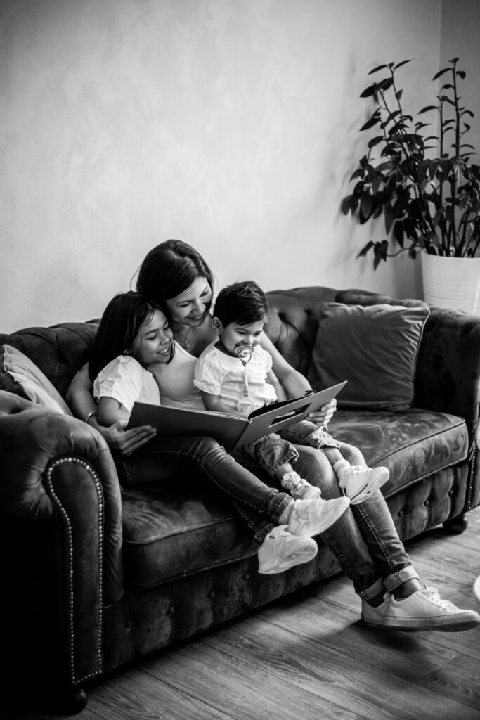 Papa et ses enfants qui lisent sur le canapé, en noir et blanc