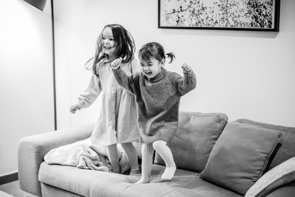 Petites filles qui sautent sur le canapé, en noir et blanc