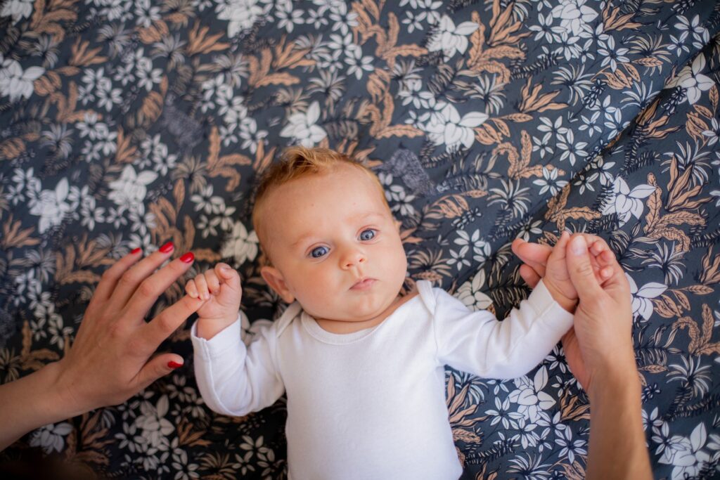 Bébé en body blanc allongé sur un tissu fleuri