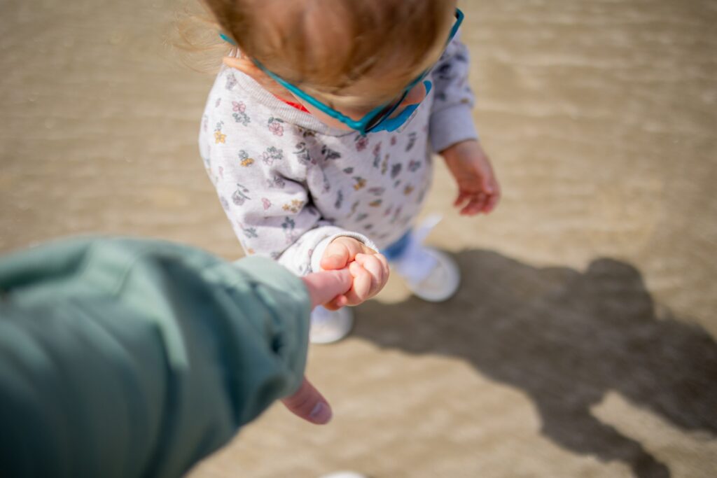 Petite fille qui tient la main de son parent