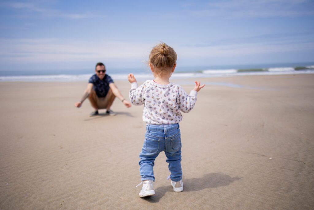 Petit garçon qui marche sur la plage vers son papa