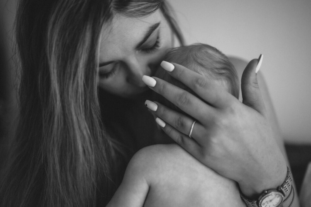 Maman qui tient la main de son bébé contre son visage, en noir et blanc