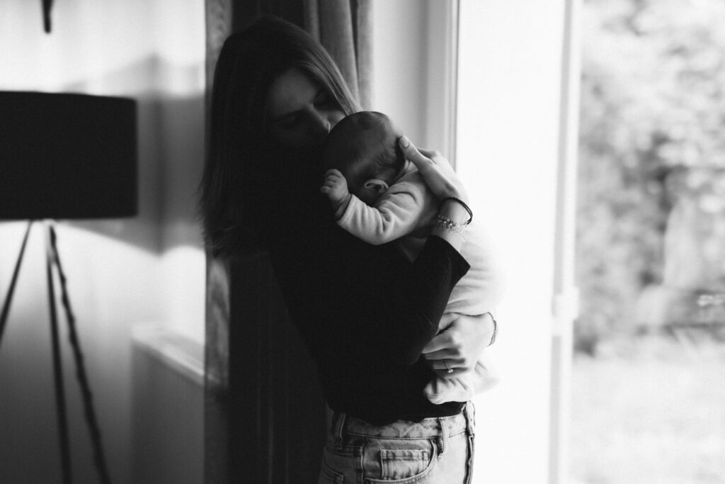 Maman qui porte son bébé près d'une fenêtre, contre-jour