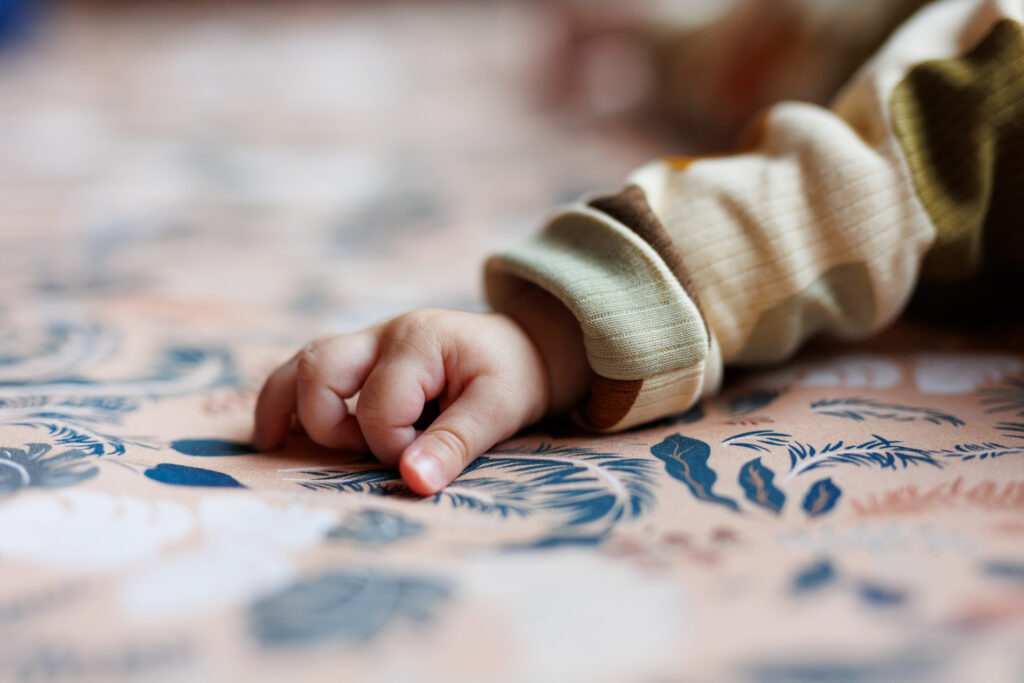 Main d'un bébé posée sur un tissu fleuri