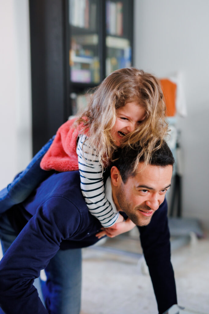 Papa qui porte sa fille sur le dos, éclats de rire à la maison