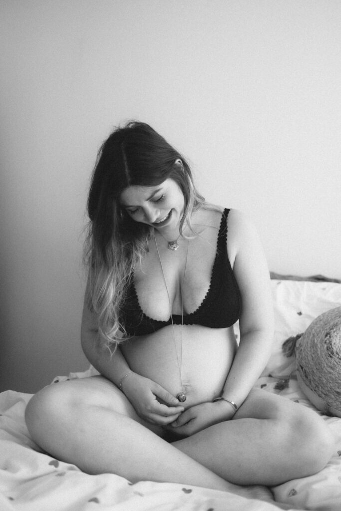 Femme enceinte assise sur le lit, en noir et blanc