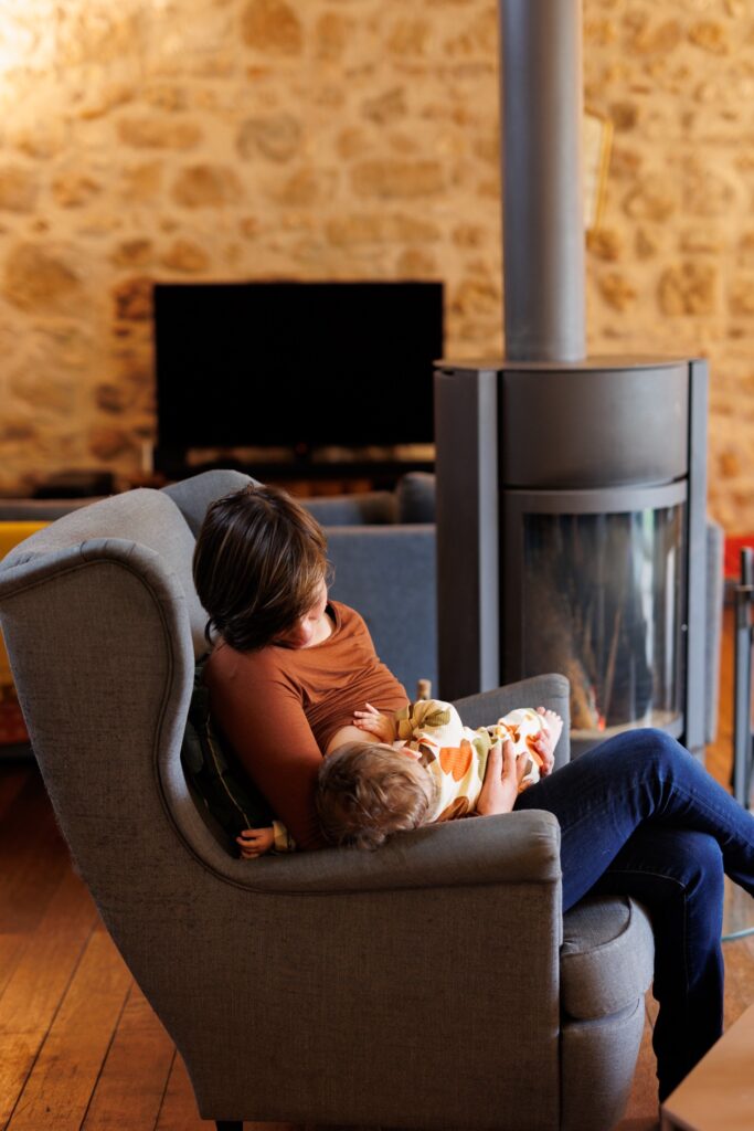 Maman et son bébé blottis dans un fauteuil près du poêle