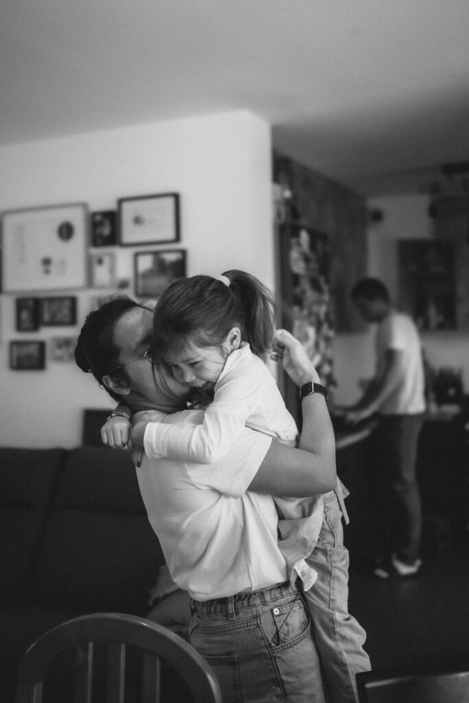 Père enlaçant fermement sa fille à la maison, portrait en noir et blanc — photographe famille Val d'Oise