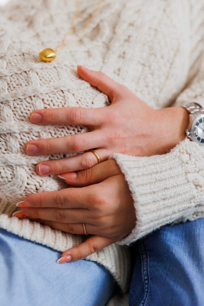 Très gros plan sur les mains et les alliances du couple entrelacées sur le ventre, noir et blanc — photographe grossesse Cergy